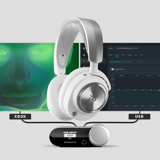 An image of Arctis Nova Pro Wireless White and base station with two monitors in the background.